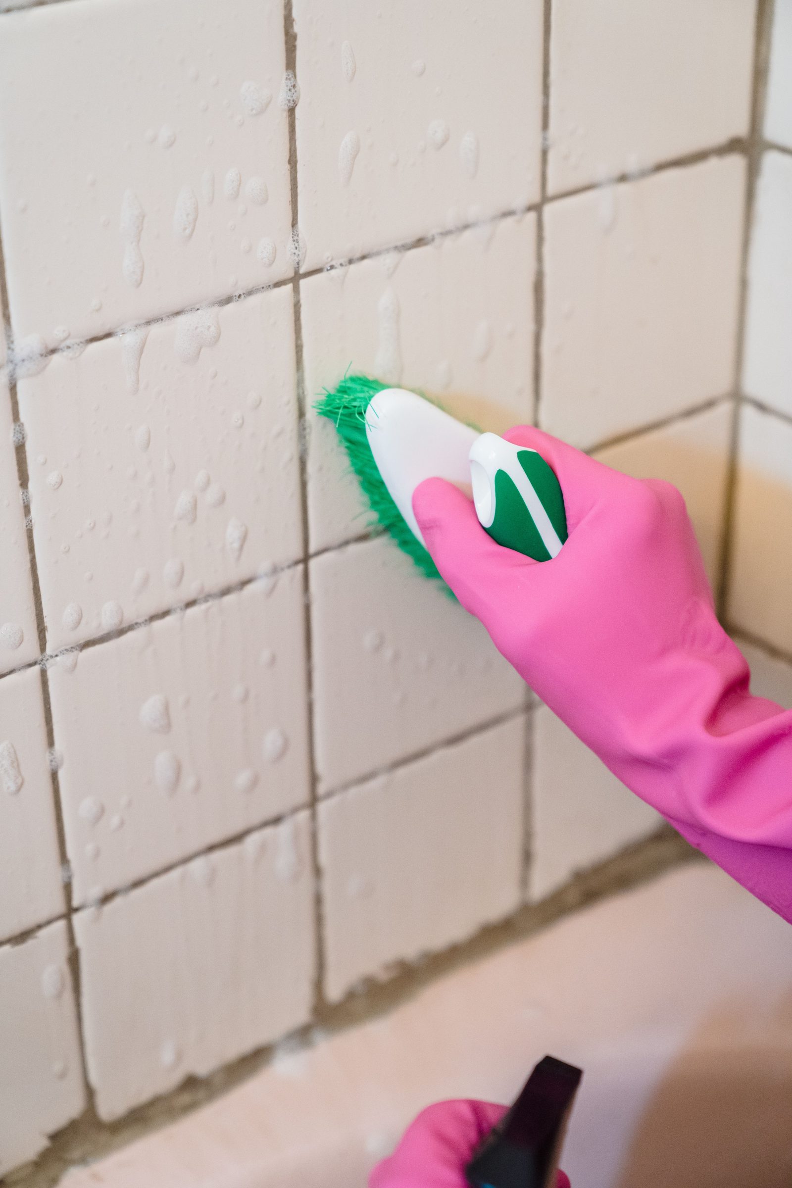 Scrubbing bathroom wall tiles during deep cleaning